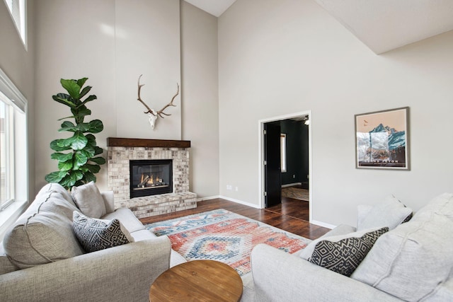 living area featuring baseboards, a high ceiling, wood finished floors, and a fireplace