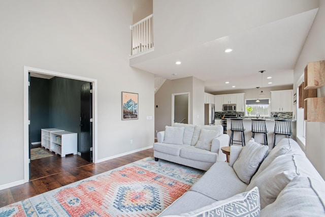 living area featuring dark wood finished floors, a high ceiling, recessed lighting, and baseboards