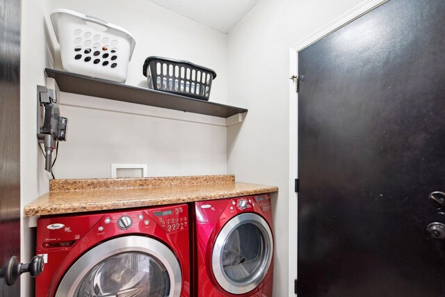 clothes washing area featuring a textured ceiling, laundry area, and washer and clothes dryer