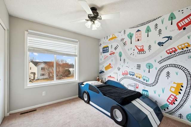 bedroom featuring visible vents, a ceiling fan, a textured ceiling, carpet floors, and baseboards