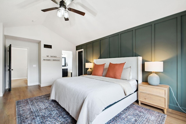 bedroom with a decorative wall, a ceiling fan, lofted ceiling, and wood finished floors