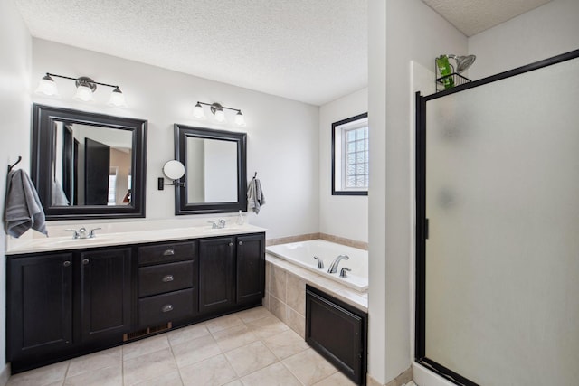 bathroom with a shower stall, a garden tub, tile patterned floors, a textured ceiling, and a sink