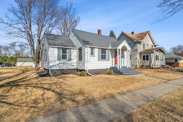 view of front facade with a shingled roof, a front lawn, and a chimney