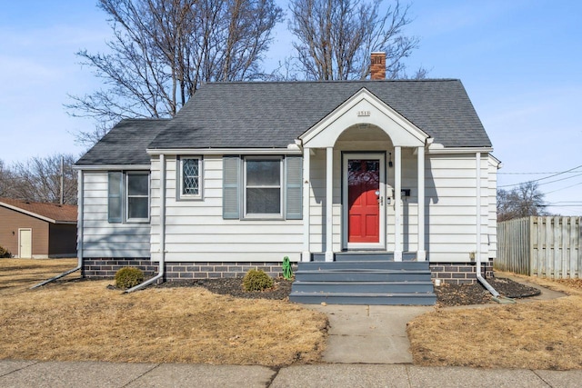 bungalow-style house with fence, a chimney, and a shingled roof