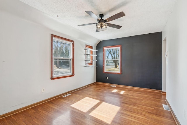 unfurnished room with visible vents, baseboards, a textured ceiling, and wood finished floors