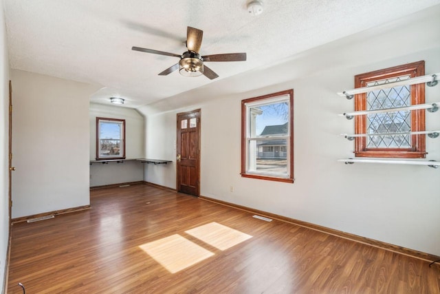 spare room with a wealth of natural light, a textured ceiling, and wood finished floors