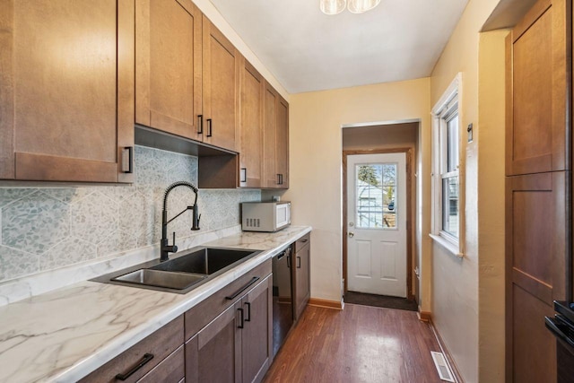 kitchen with dark wood-type flooring, a sink, backsplash, white microwave, and dishwasher