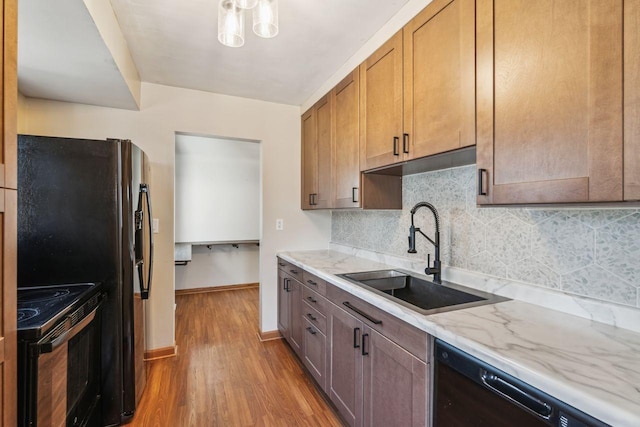 kitchen featuring a sink, backsplash, wood finished floors, black / electric stove, and dishwasher