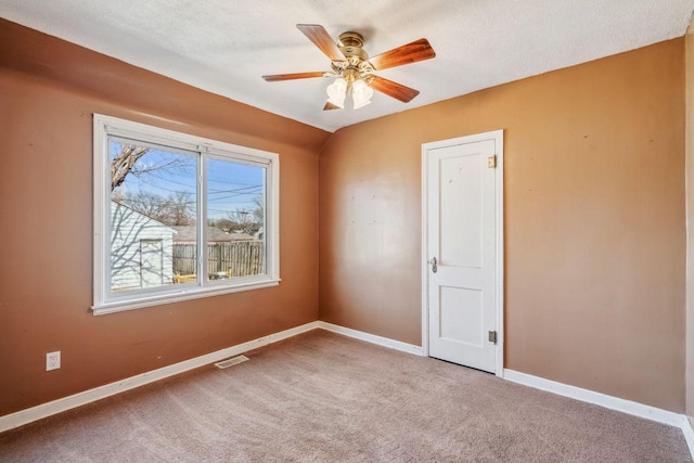 empty room with carpet, baseboards, visible vents, ceiling fan, and a textured ceiling