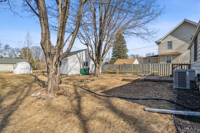 view of yard with an outbuilding, fence, a shed, a wooden deck, and central AC