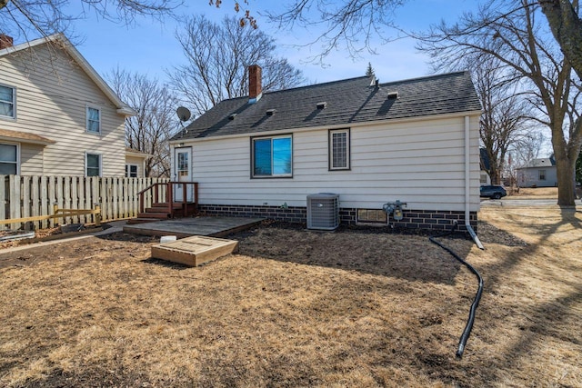 rear view of house with central air condition unit, fence, roof with shingles, and a chimney