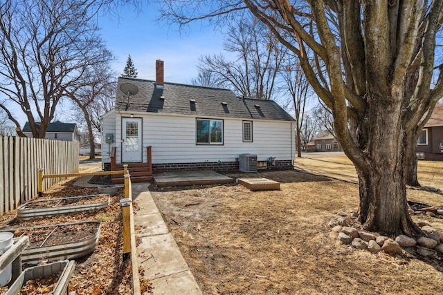 back of house with central air condition unit, fence, roof with shingles, a vegetable garden, and a chimney