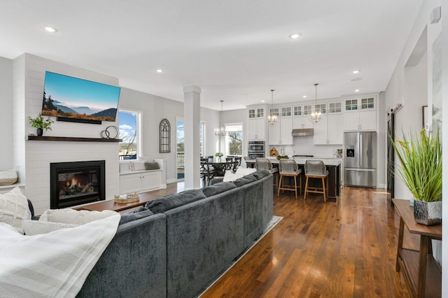 living room featuring a large fireplace, dark wood finished floors, a wealth of natural light, and recessed lighting