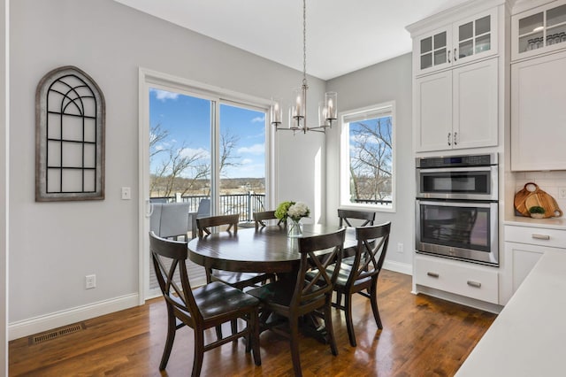 dining space featuring visible vents, dark wood finished floors, a notable chandelier, and baseboards