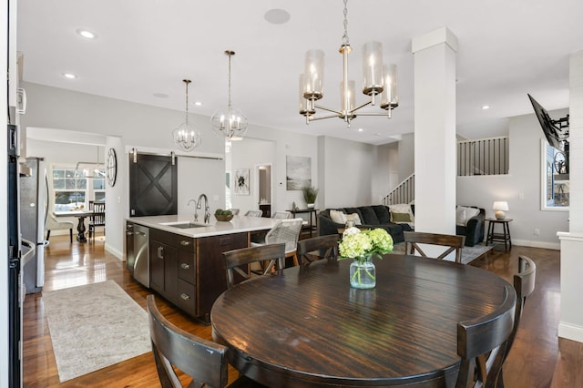 dining room with a barn door, stairway, dark wood finished floors, and recessed lighting