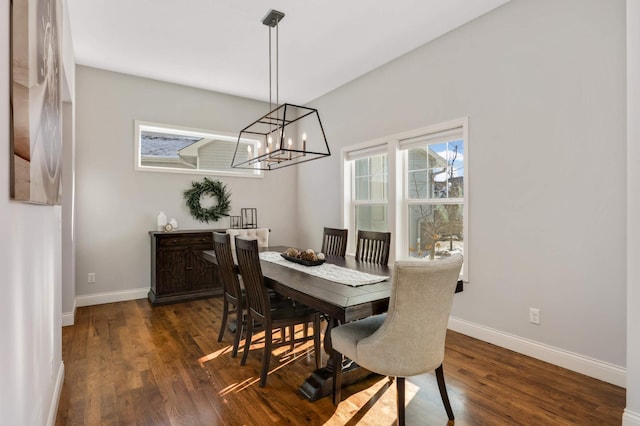 dining area featuring a chandelier, dark wood finished floors, and baseboards