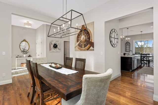 dining area featuring dark wood-style floors, baseboards, and a notable chandelier