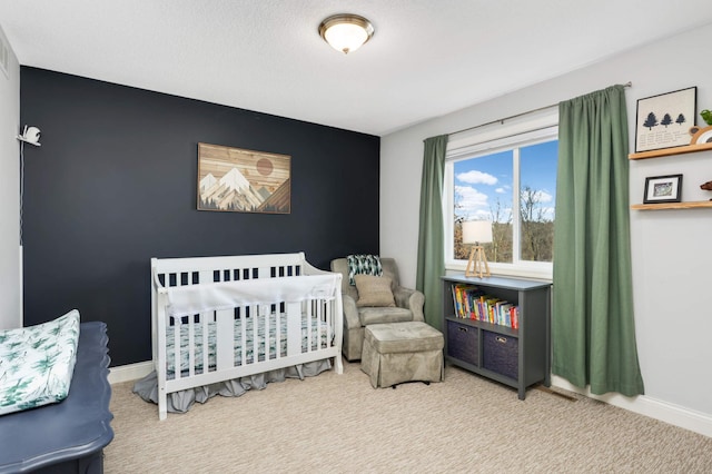 bedroom featuring carpet floors, a crib, and baseboards