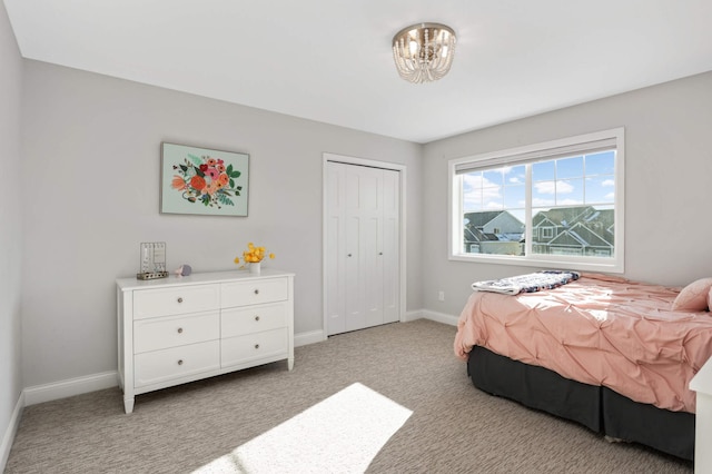 bedroom featuring baseboards, a closet, an inviting chandelier, and light colored carpet