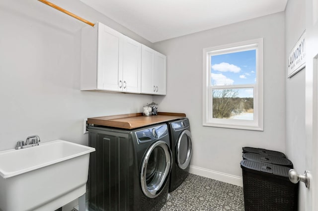 laundry area featuring cabinet space, baseboards, washer and clothes dryer, and a sink