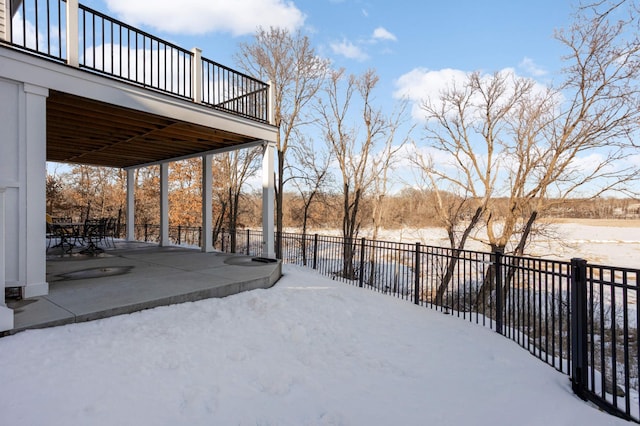 yard layered in snow with a patio area and fence