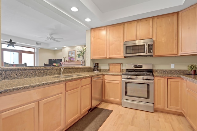 kitchen with light brown cabinets, stainless steel appliances, and a sink