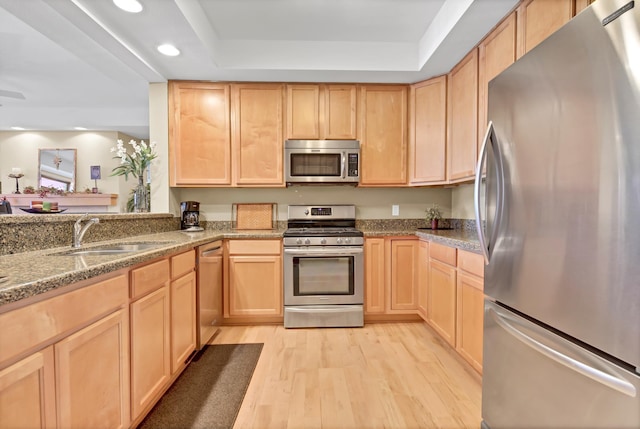 kitchen with a sink, stainless steel appliances, light wood-style flooring, and light brown cabinets