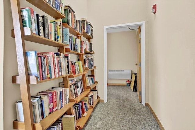 hall featuring a wall mounted AC, baseboards, and carpet floors