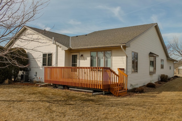 back of property with a deck, central air condition unit, a lawn, and roof with shingles