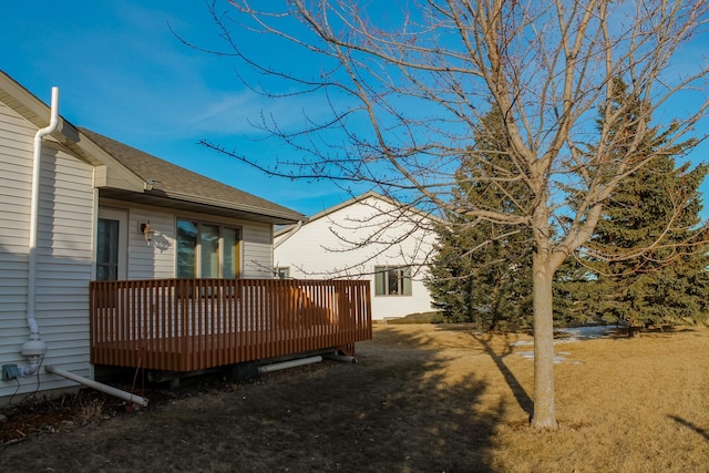 exterior space featuring a wooden deck, a yard, and roof with shingles