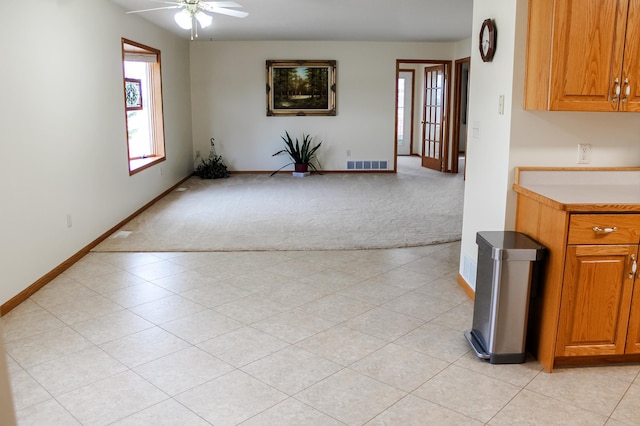 kitchen with visible vents, baseboards, light countertops, light colored carpet, and brown cabinets