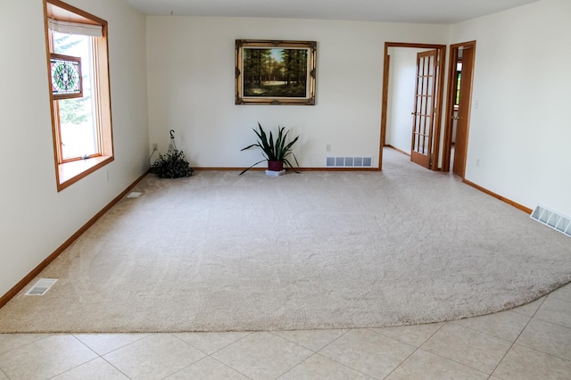 carpeted spare room with tile patterned floors, baseboards, and visible vents