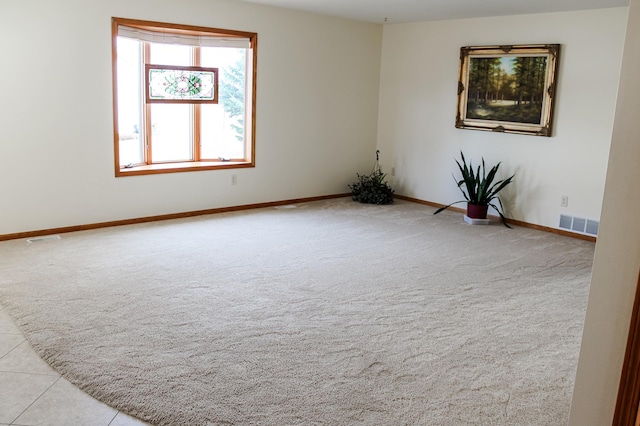 carpeted empty room with tile patterned floors, baseboards, and visible vents