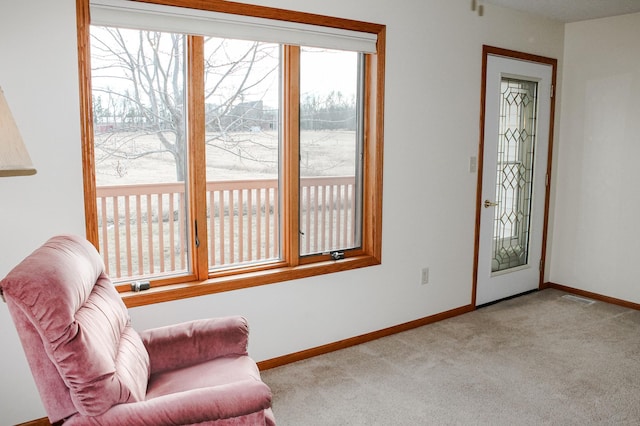 living area with a wealth of natural light, visible vents, baseboards, and carpet