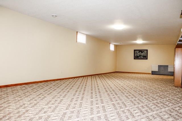 below grade area featuring baseboards and light carpet