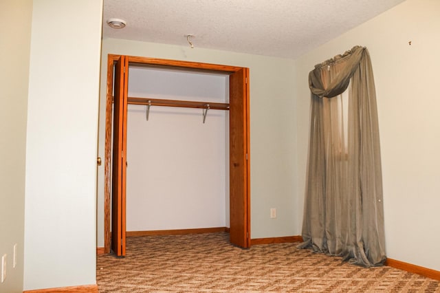 unfurnished bedroom with carpet, baseboards, a closet, and a textured ceiling