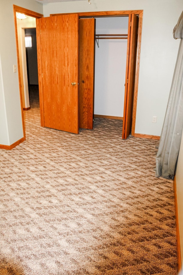 unfurnished bedroom featuring carpet flooring, baseboards, and a closet