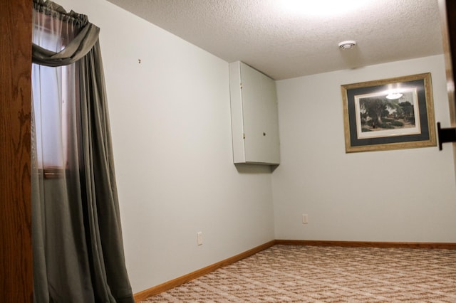 spare room featuring baseboards, carpet, and a textured ceiling