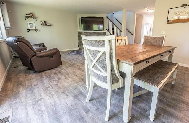 dining space featuring stairway, wood finished floors, visible vents, and baseboards