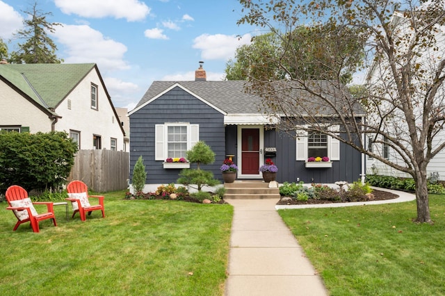 bungalow-style house with board and batten siding, a front yard, fence, and a shingled roof