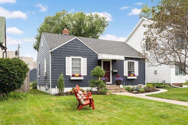 view of front facade featuring a chimney, roof with shingles, a front yard, and board and batten siding