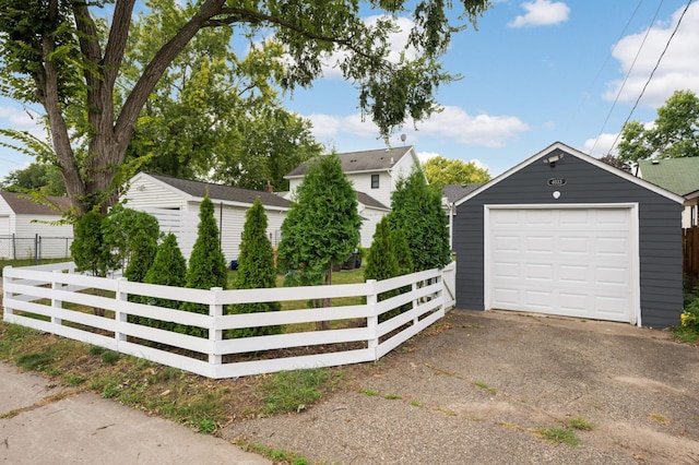 detached garage featuring driveway and fence