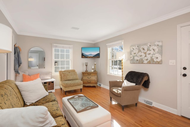 living room with light wood-style flooring, visible vents, baseboards, and crown molding