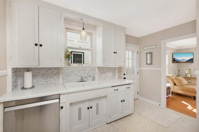 kitchen with light countertops, stainless steel dishwasher, a sink, and tasteful backsplash