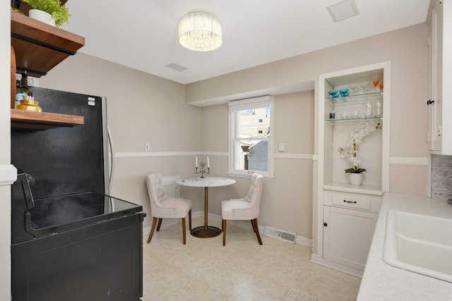 kitchen featuring a sink, visible vents, white cabinets, light countertops, and freestanding refrigerator