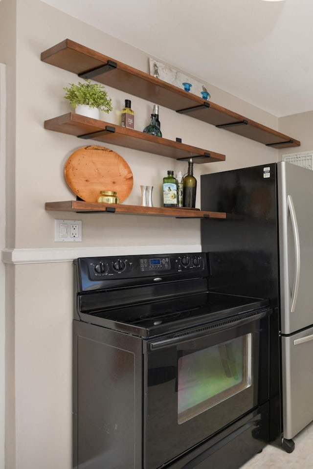 kitchen with freestanding refrigerator, black range with electric cooktop, and open shelves