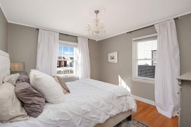 bedroom featuring light wood-style floors, baseboards, multiple windows, and a chandelier