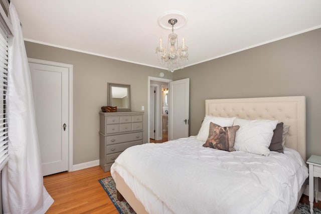 bedroom featuring a chandelier, crown molding, light wood-type flooring, and baseboards