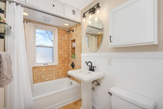 bathroom featuring shower / bath combination with curtain, wainscoting, toilet, and tile patterned floors