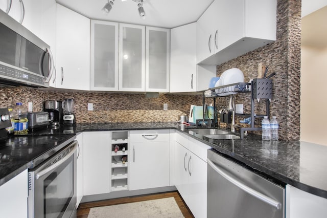 kitchen with backsplash, white cabinets, stainless steel appliances, and glass insert cabinets